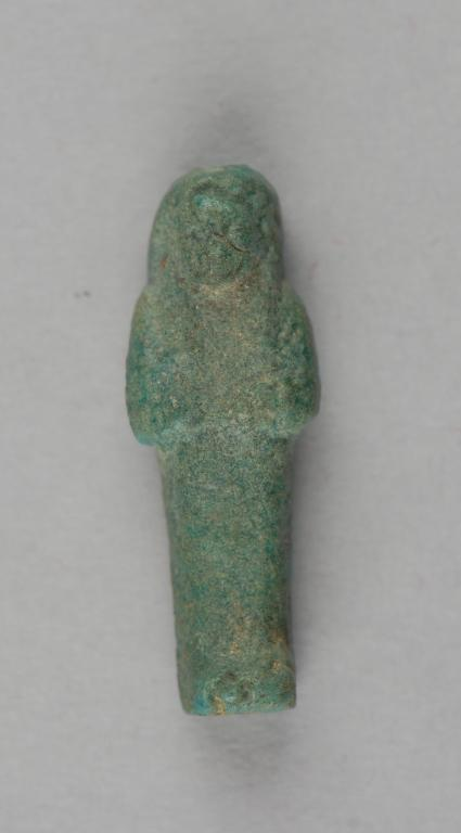 A small green faience shabti figure, arms crossed over its chest, from an Egyptian burial